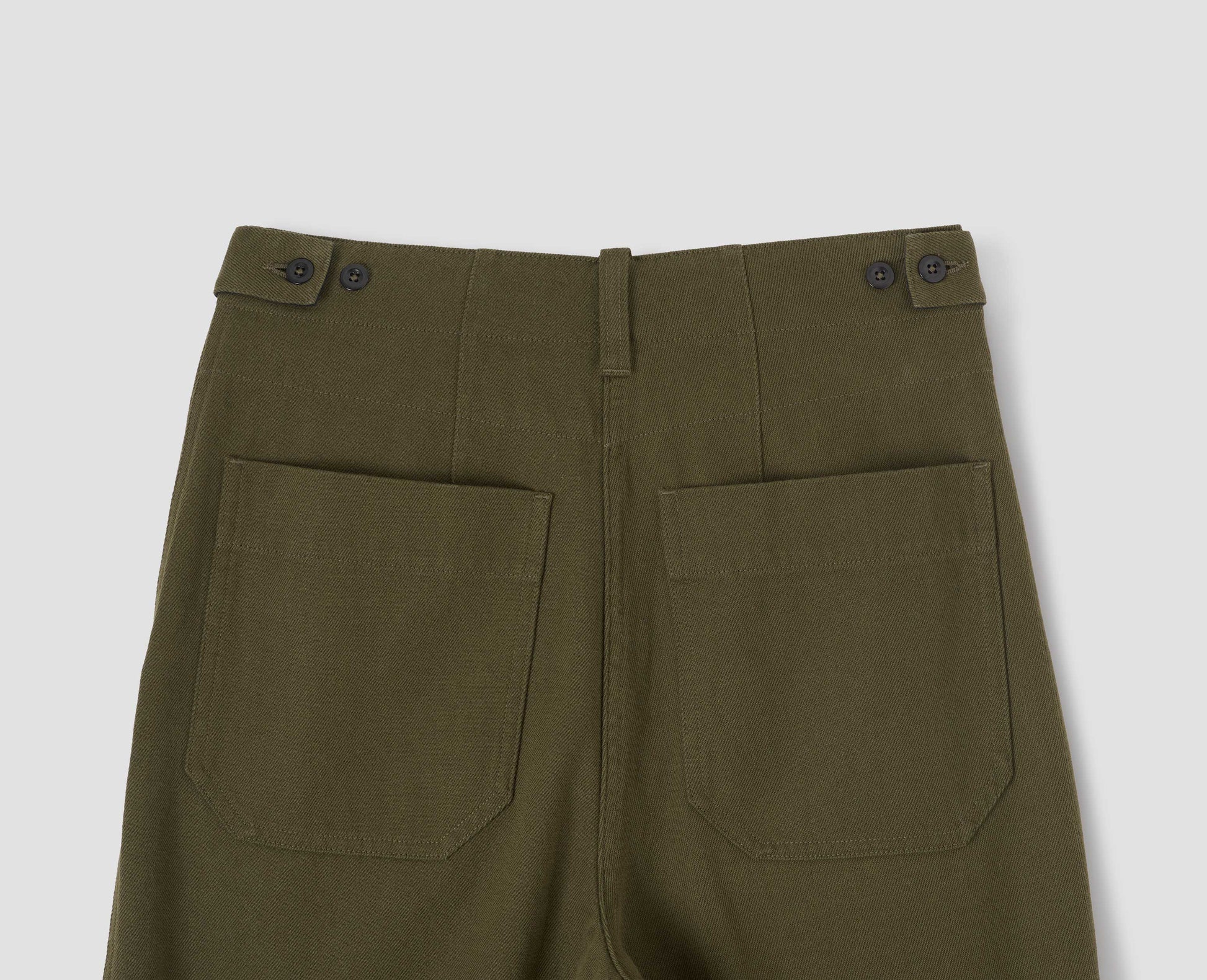 Green cotton wool trousers with button tab side adjusters, belt loop and patch back pockets. Back flat lay view.