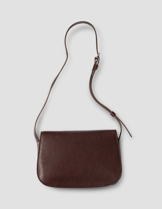Brown fine grain leather satchel bag with adjustable shoulder strap. Back flat lay view. 