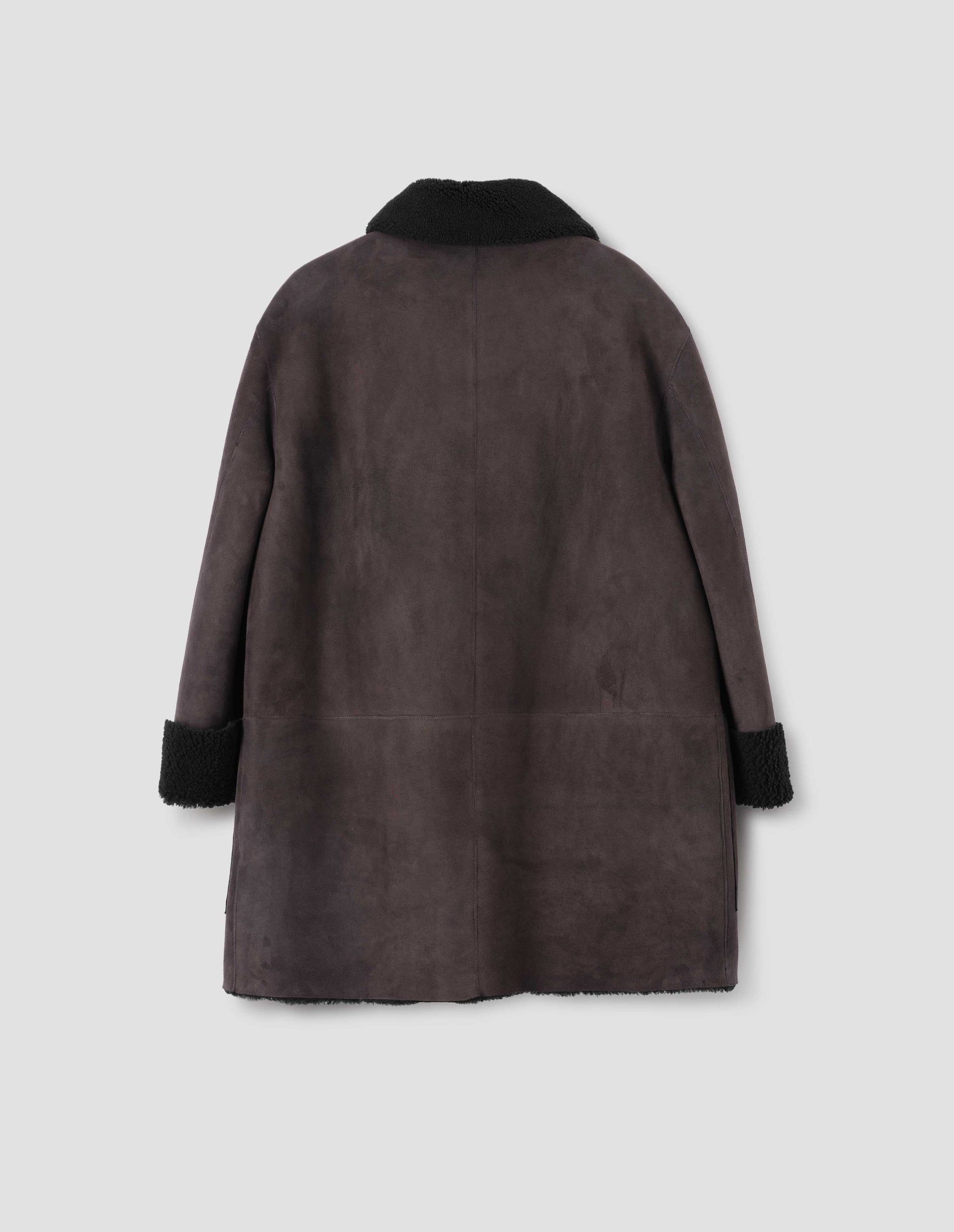 Brown and black merino sheepskin car coat with contrast sleeves and collar. Back flat lay view.