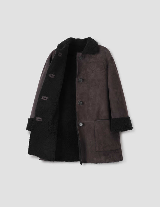 Brown and black merino sheepskin car coat with storm tab on collar, patch pockets and horn button closure. Front open flat lay view.