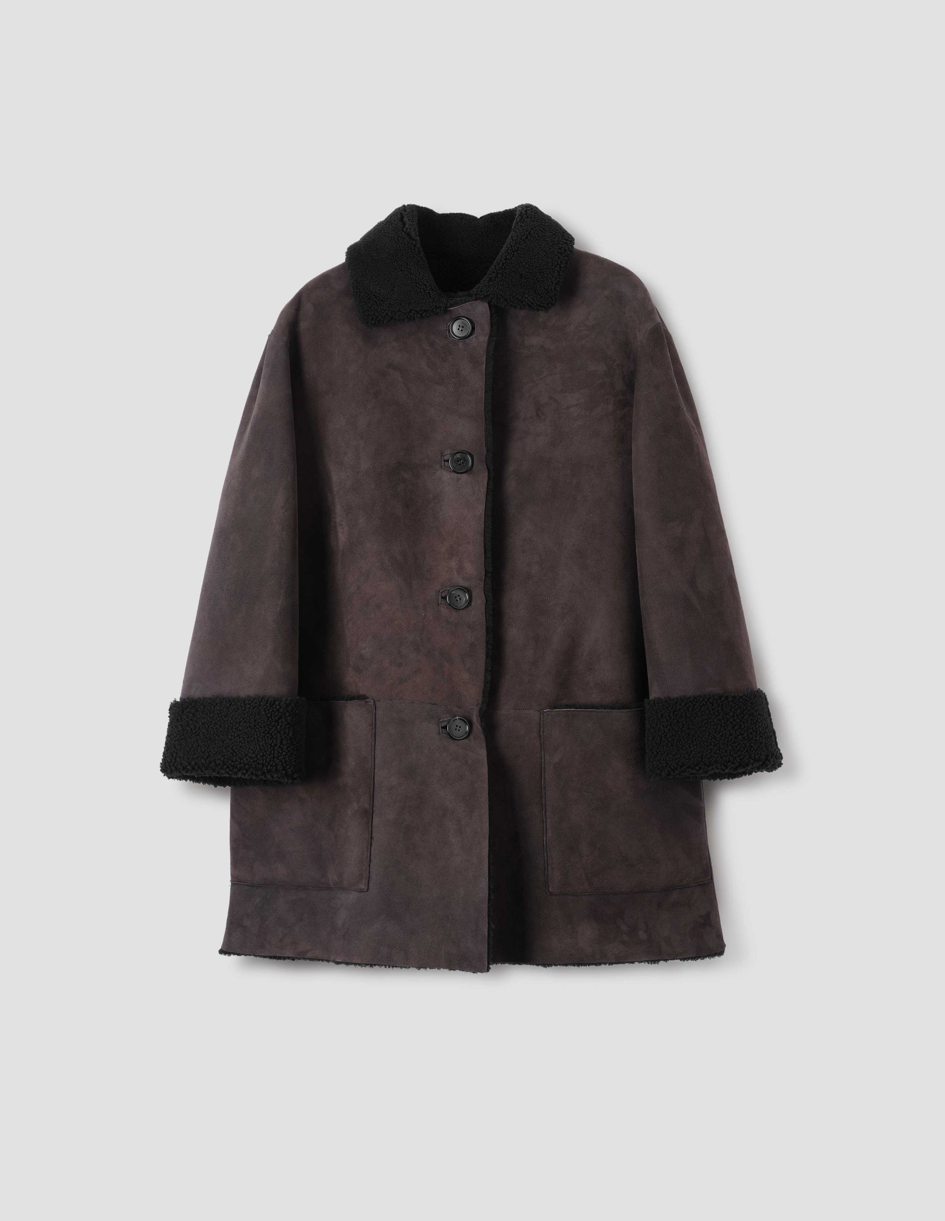 Brown and black merino sheepskin car coat with storm tab on collar, patch pockets and horn button closure. Front flat lay view.