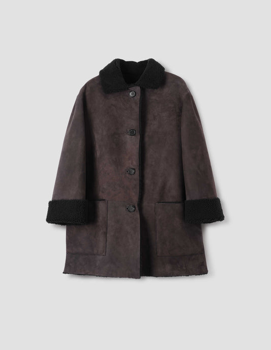 Brown and black merino sheepskin car coat with storm tab on collar, patch pockets and horn button closure. Front flat lay view.