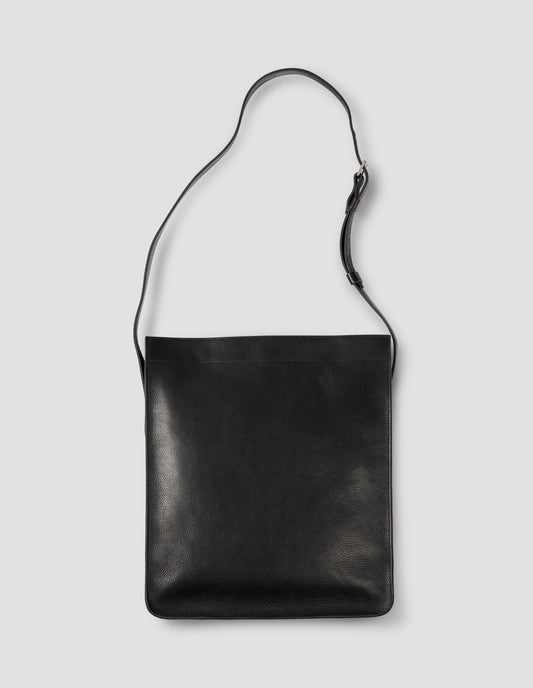 Black fine grain leather tote bag with a roller buckle adjustable shoulder strap and hand-stained turned-out seams. Front flat lay view.