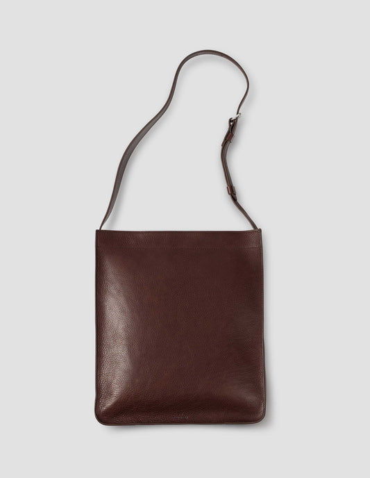 Brown fine grain leather tote bag with a roller buckle adjustable shoulder strap and hand-stained turned-out seams. Front flat lay view.