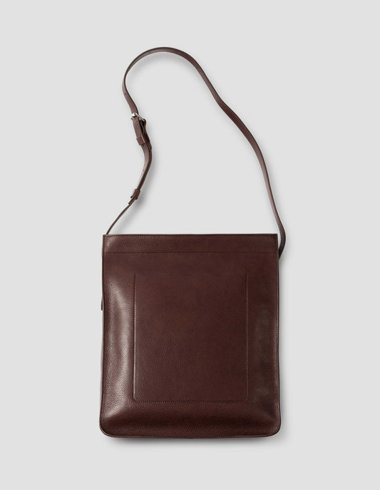 Brown fine grain leather tote bag with a roller buckle adjustable shoulder strap, large internal stitch-through sleeve pocket and hand-stained turned-out seams. Back flat lay view.