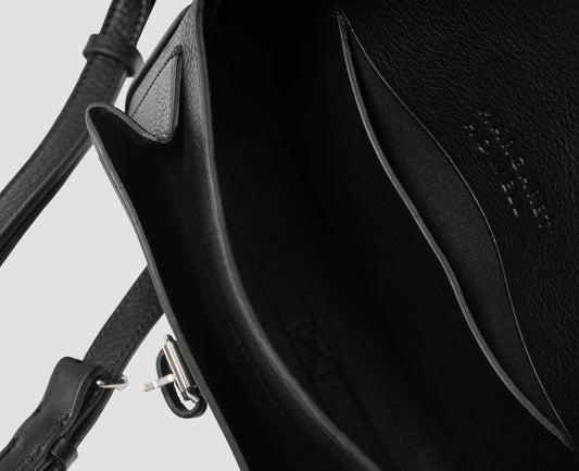 Black fine grain leather small satchel bag with pleat expandable exterior pocket and interior slip pocket and embossed Margaret Howell logo detail. Fabric swatch.