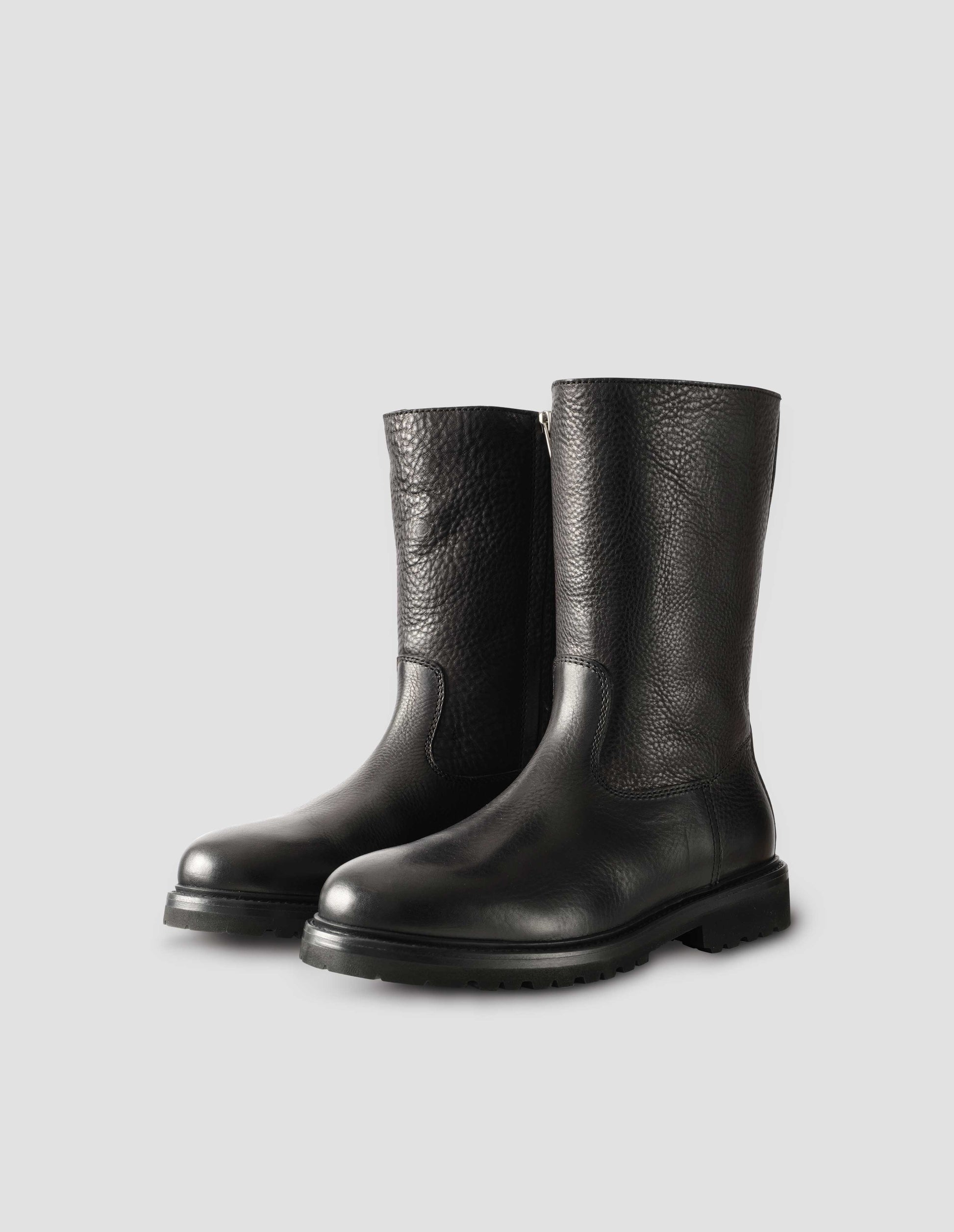 Black leather three quarter length boots with Vibram sole and shearling lining. Side view flat lay.