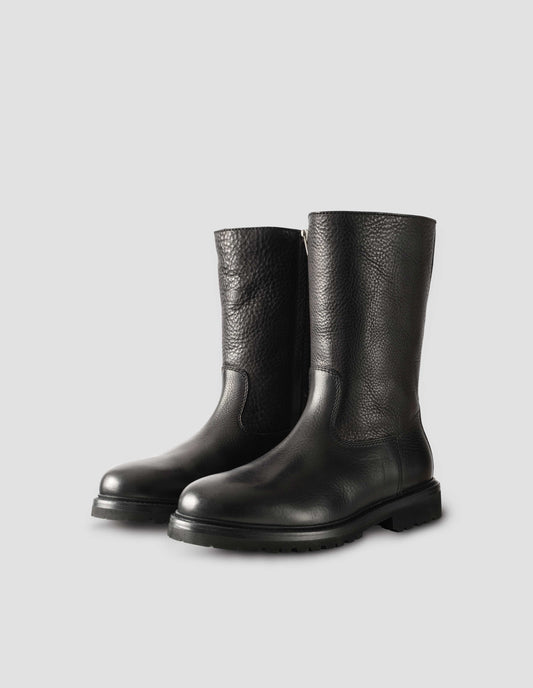 Black leather three quarter length boots with Vibram sole and shearling lining. Side view flat lay.