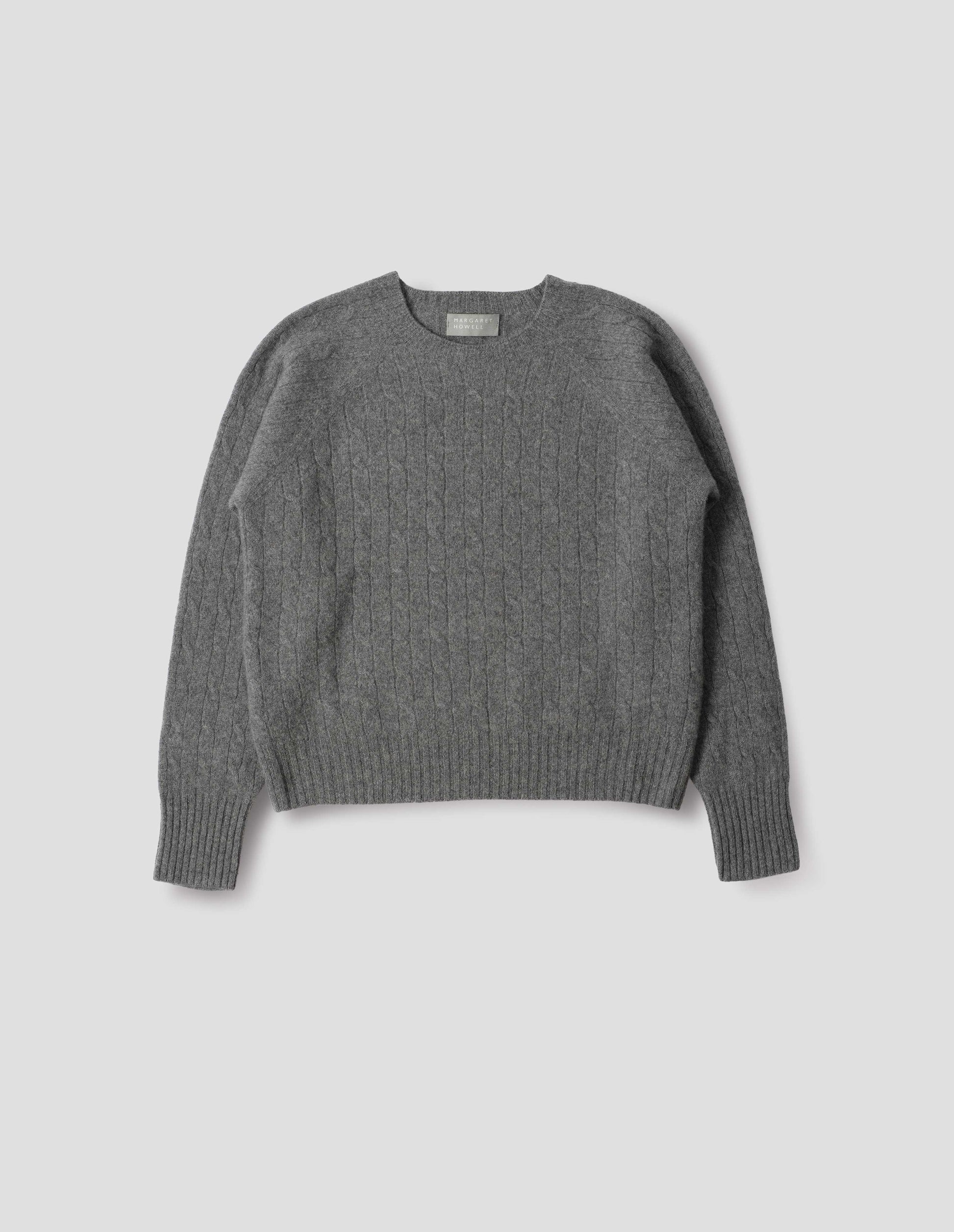 Grey cable knit long sleeve jumper with raglan sleeve and contrast rib on neck, cuffs and hem. Front flat lay view.
