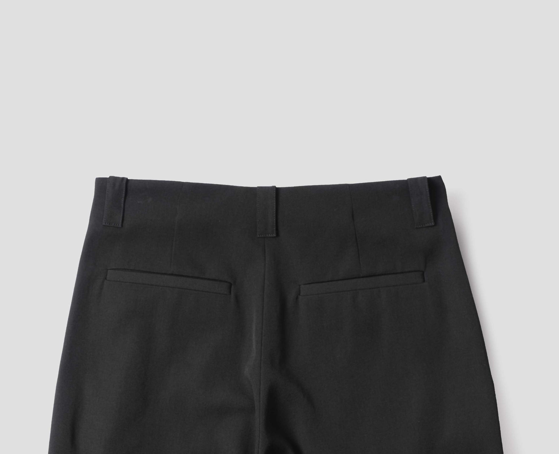 Black wool wide leg culottes, with belt loops, side pockets and welt back pockets. Back flat lay view.