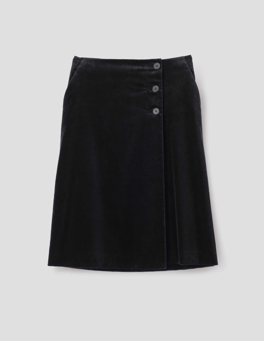 Black velvet a-line skirt with deep wrap, horn button fastening and slant side pockets. Front flat lay view.