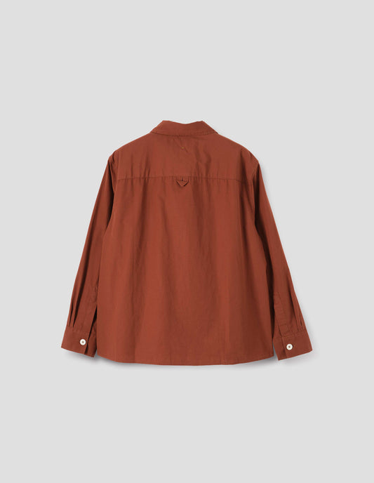 Brownish red shirt with corozo button cuffs, hang loop on back yoke and gusset stitching. Back flat lay view. 