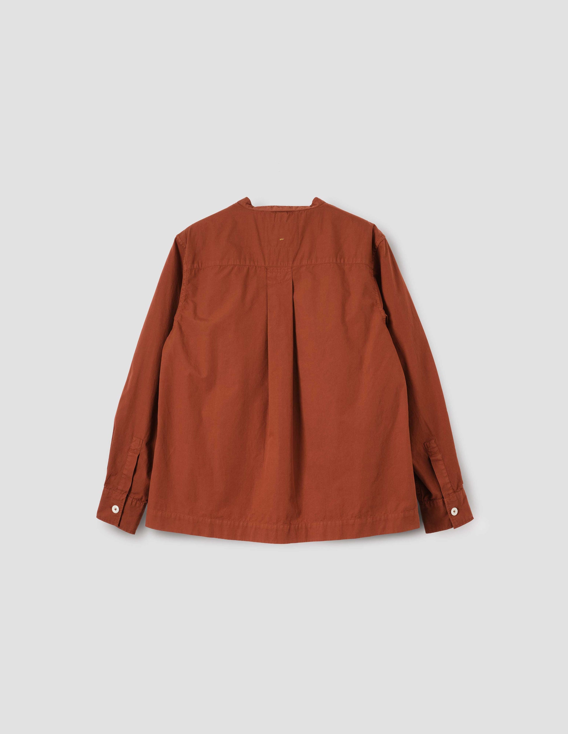 Brownish red collarless shirt with corozo brace button cuffs and buttonhole detailing on neck band and box pleat on back yoke. Back flat lay view.