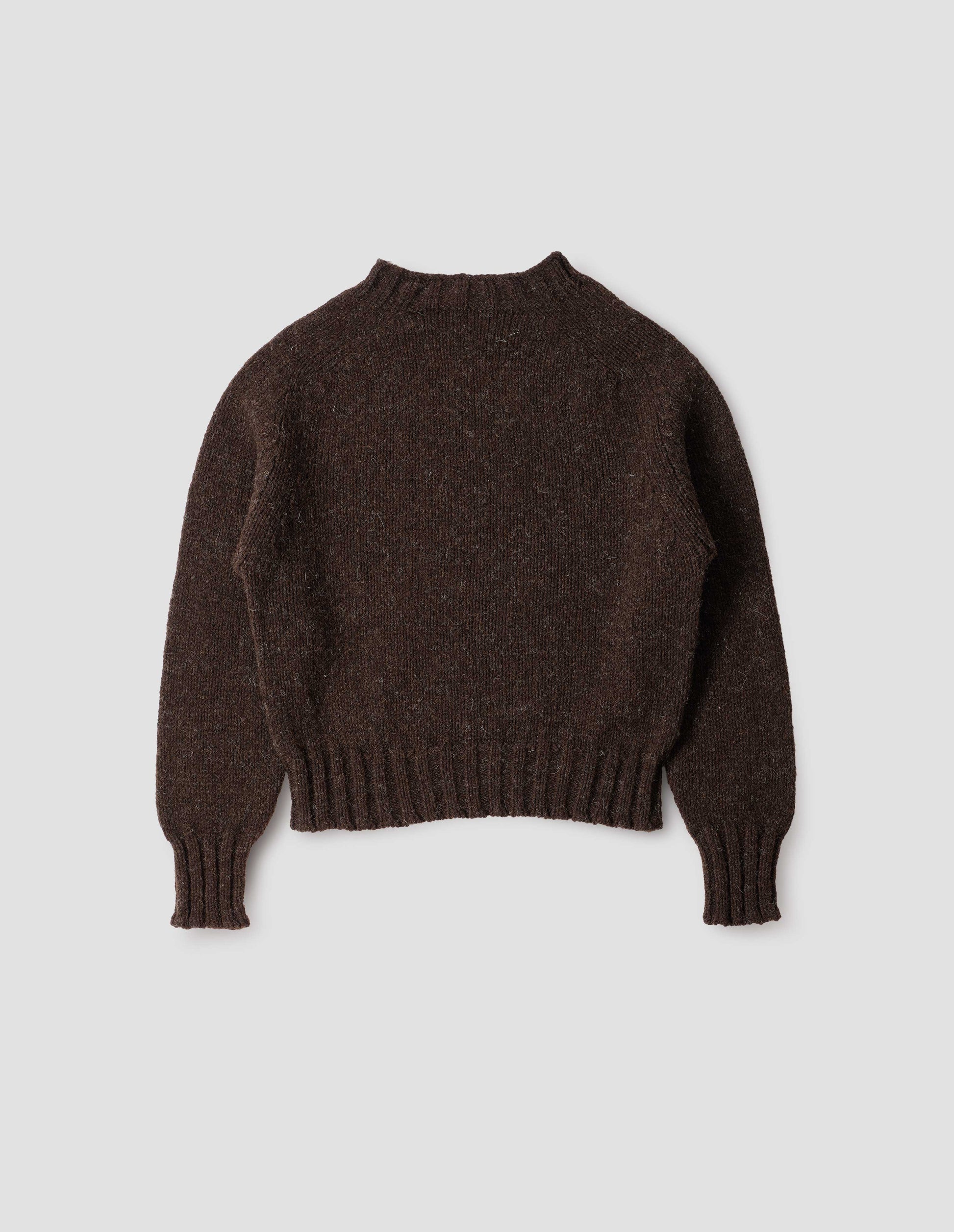 Dark brown rustic wool jumper with saddle sleeve and contrasting rib on neck, cuffs and hem. Back flat lay view.