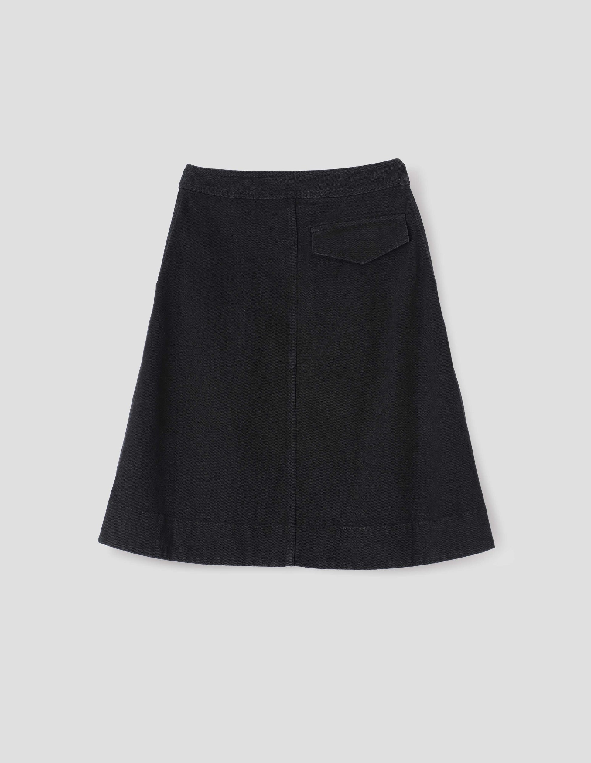 Black A-line skirt with deep stitch hem and back flap pocket, back flat lay view.