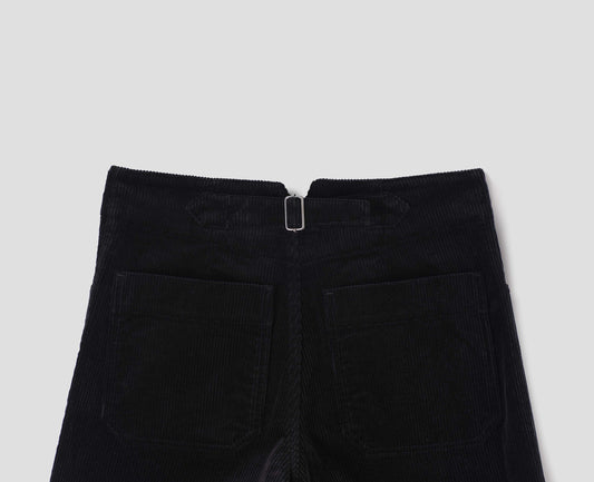 Black heavy corduroy trousers with deep stitch-through hem, patch back pockets and cinch waist adjusters. Back flat lay view.