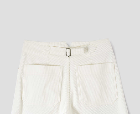 White heavy corduroy trousers with deep stitch-through hem, patch back pockets and cinch waist adjusters. Back flat lay view.