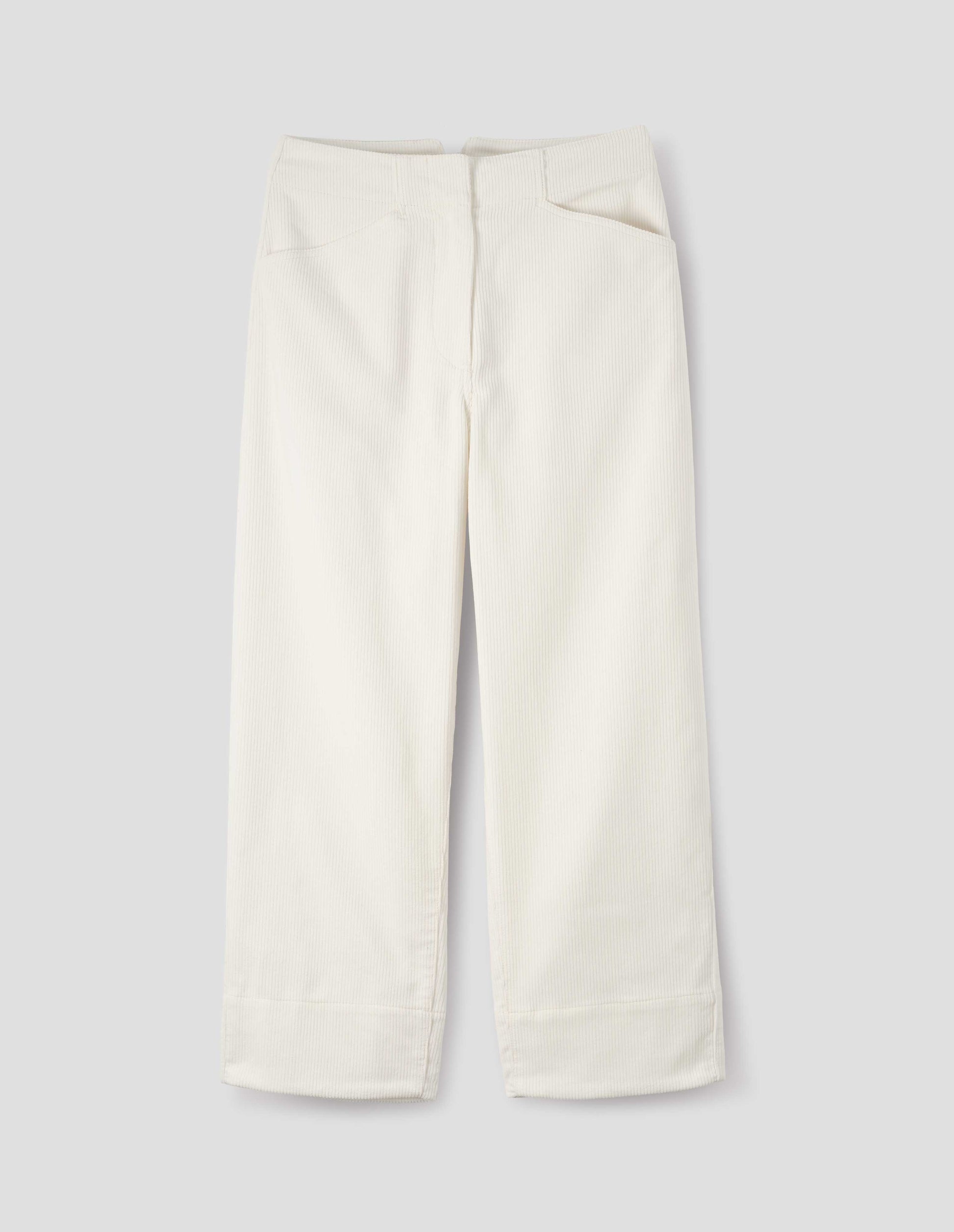 White heavy corduroy trousers with concealed double hook and bar fastening, frog pockets and deep stitch-through hem. Front flat lay view.
