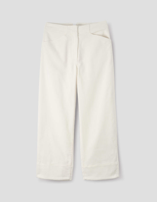 White heavy corduroy trousers with concealed double hook and bar fastening, frog pockets and deep stitch-through hem. Front flat lay view.