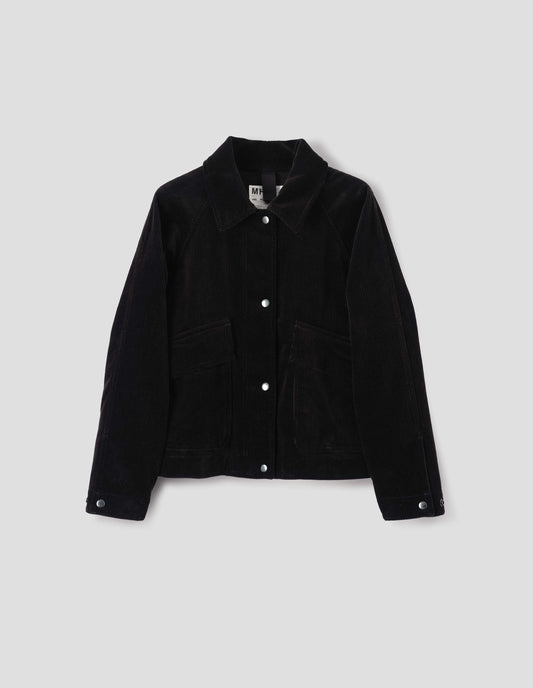 Black heavy corduroy raglan sleeve jacket, with press stud fastening offset placket, slant patch pockets with storm flap closure and adjustable cuffs. Front flat lay view. 