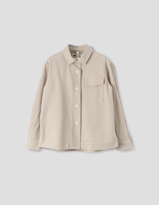 Beige oversized shirt with stitch through raised placket, corozo button fastening, patch chest pocket and deep stitch hem. Front flat lay view. 