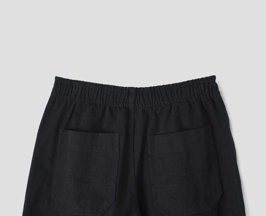 Black joggers with elasticated waistband and patch back pockets with reinforced stitch detailing, back flat lay view.