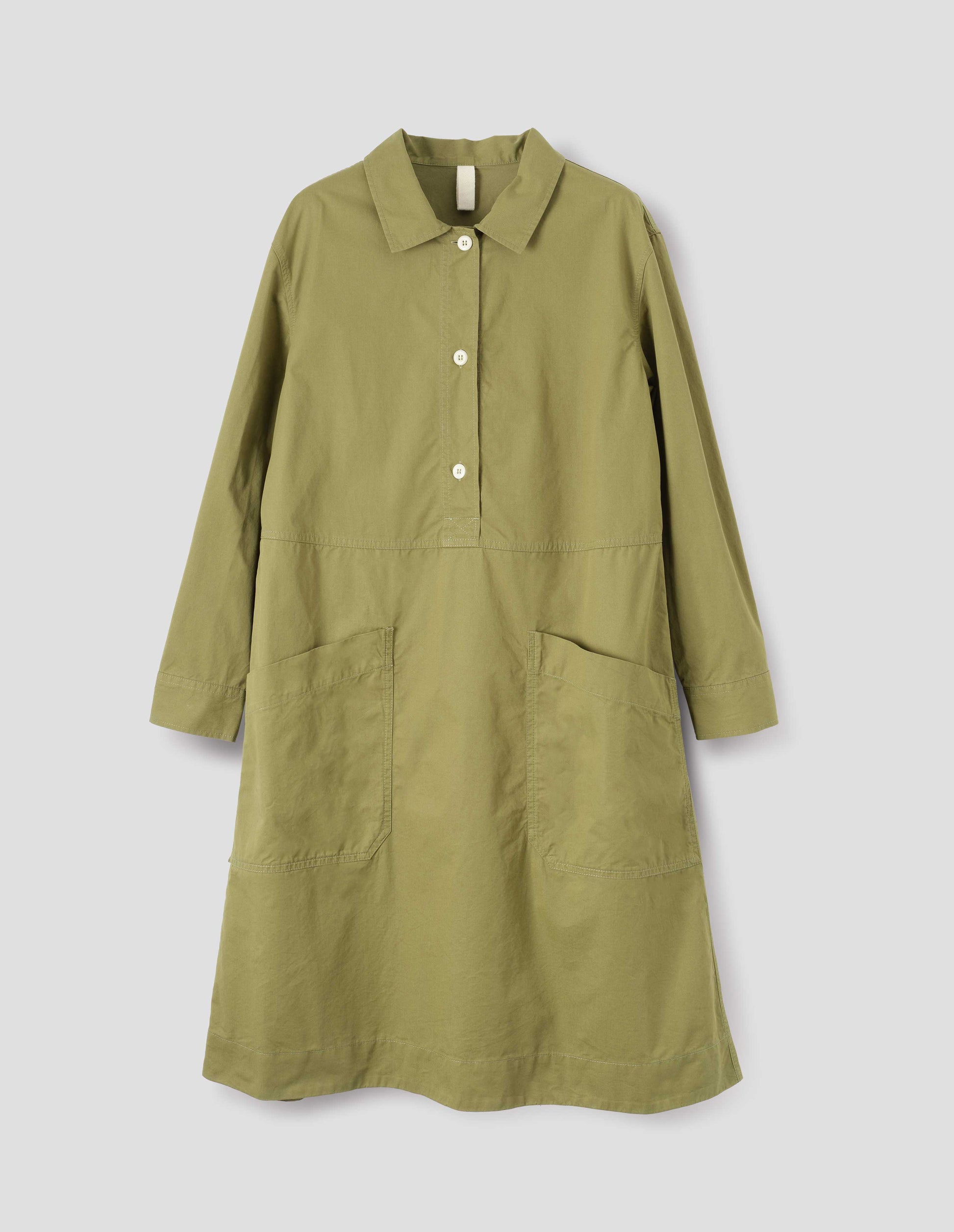 Green long sleeve shirt dress with box stitch detailing, large apron patch pockets, deep stitch hem and waist seam detail. Front flat lay view.