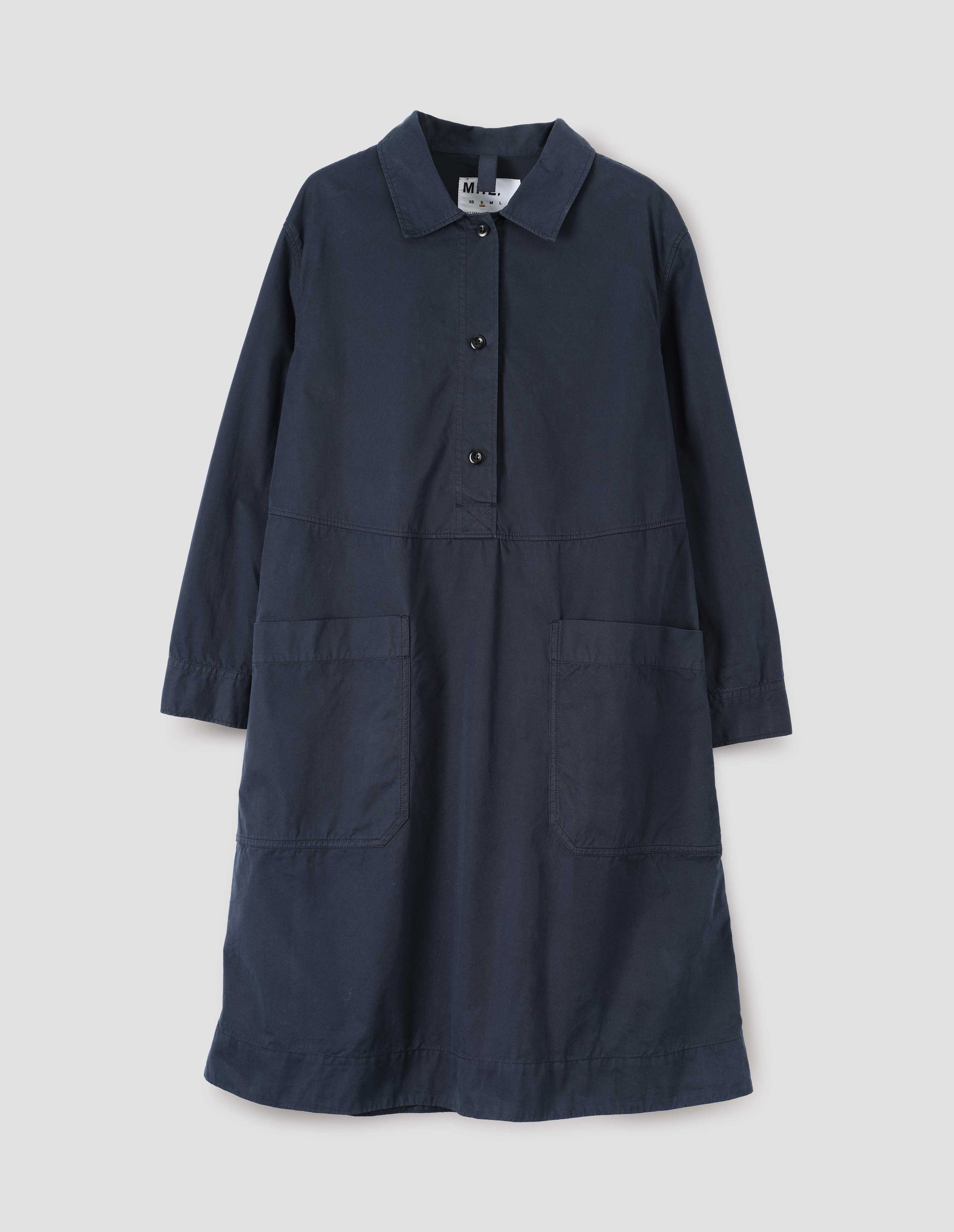Dark blue long sleeve shirt dress with box stitch detailing, large apron patch pockets, deep stitch hem and waist seam detail. Front flat lay view.
