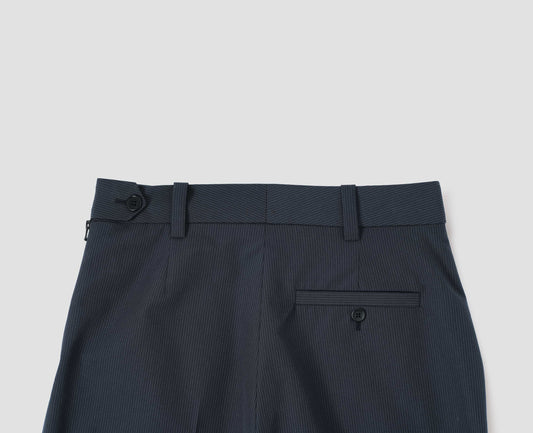 Dark blue and grey striped trousers with belt loops and side zip, horn button tab waist fastening and welt button-through back pocket. Back flat lay view.