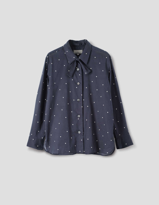 Navy and white polka dot long sleeve shirt with wide stitch through placket, mother of pearl buttons, elongated back and removeable self fabric tie. Front flat lay view.