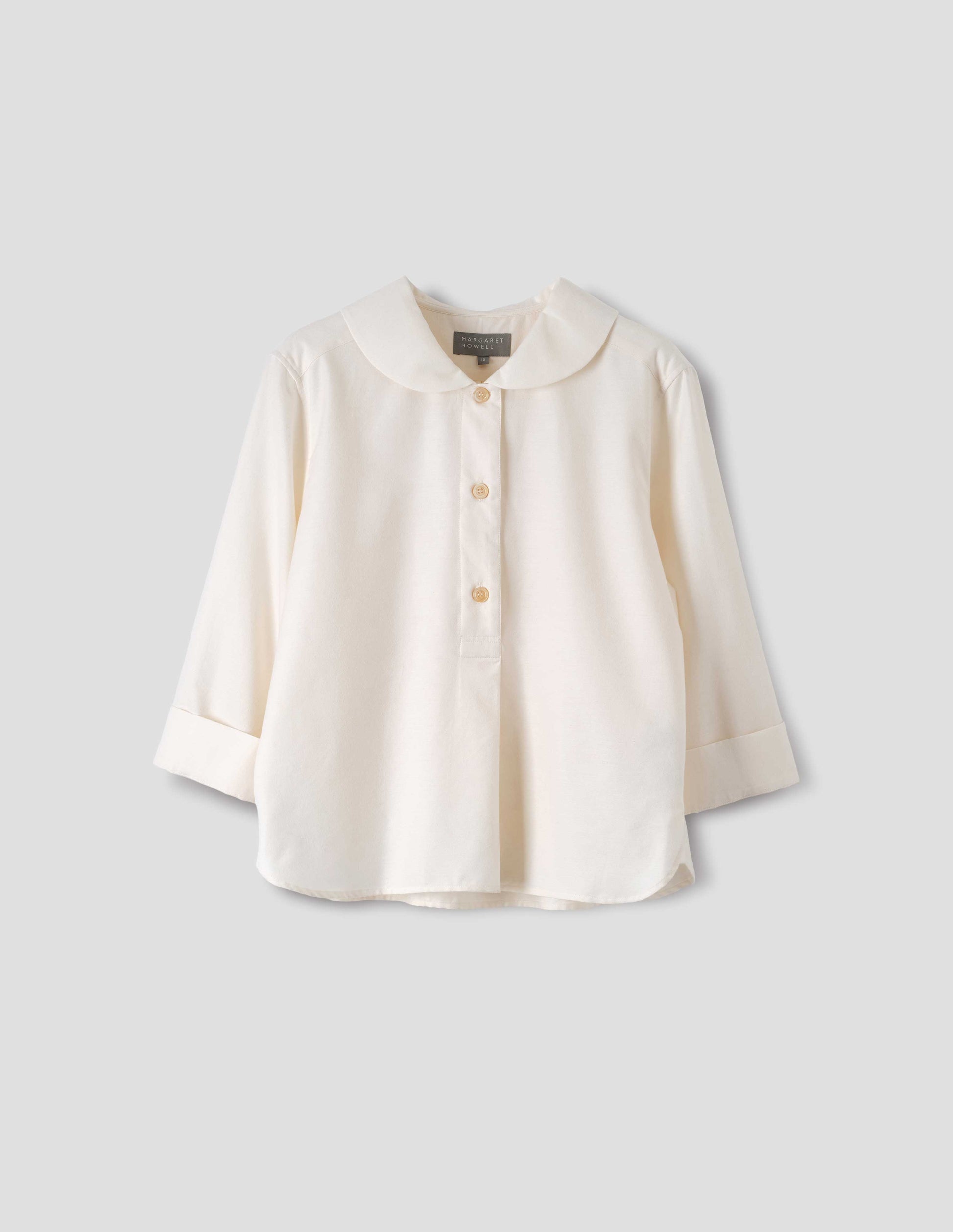 Off white petal collar shirt with three quarter length sleeves, stitch through half placket, mother of pearl buttons and turned back cuff details. Front flat lay view.