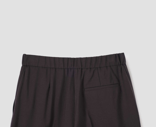 Dark brown trousers with half-elasticated waistband and welt back pocket, back flat lay view.