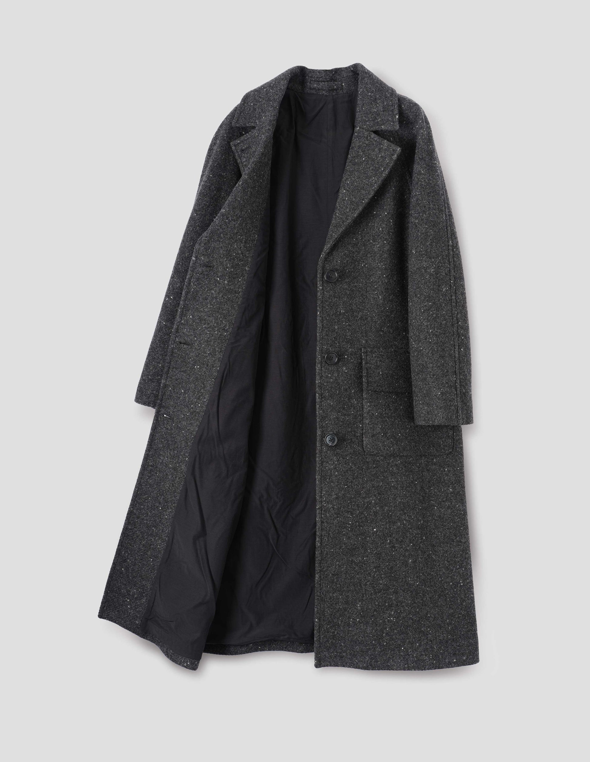 Charcoal grey heavy wool longline overcoat with raglan sleeve, button fastening lapel and deep flap patch pockets and fully lined in black cotton. Front flat lay open view.