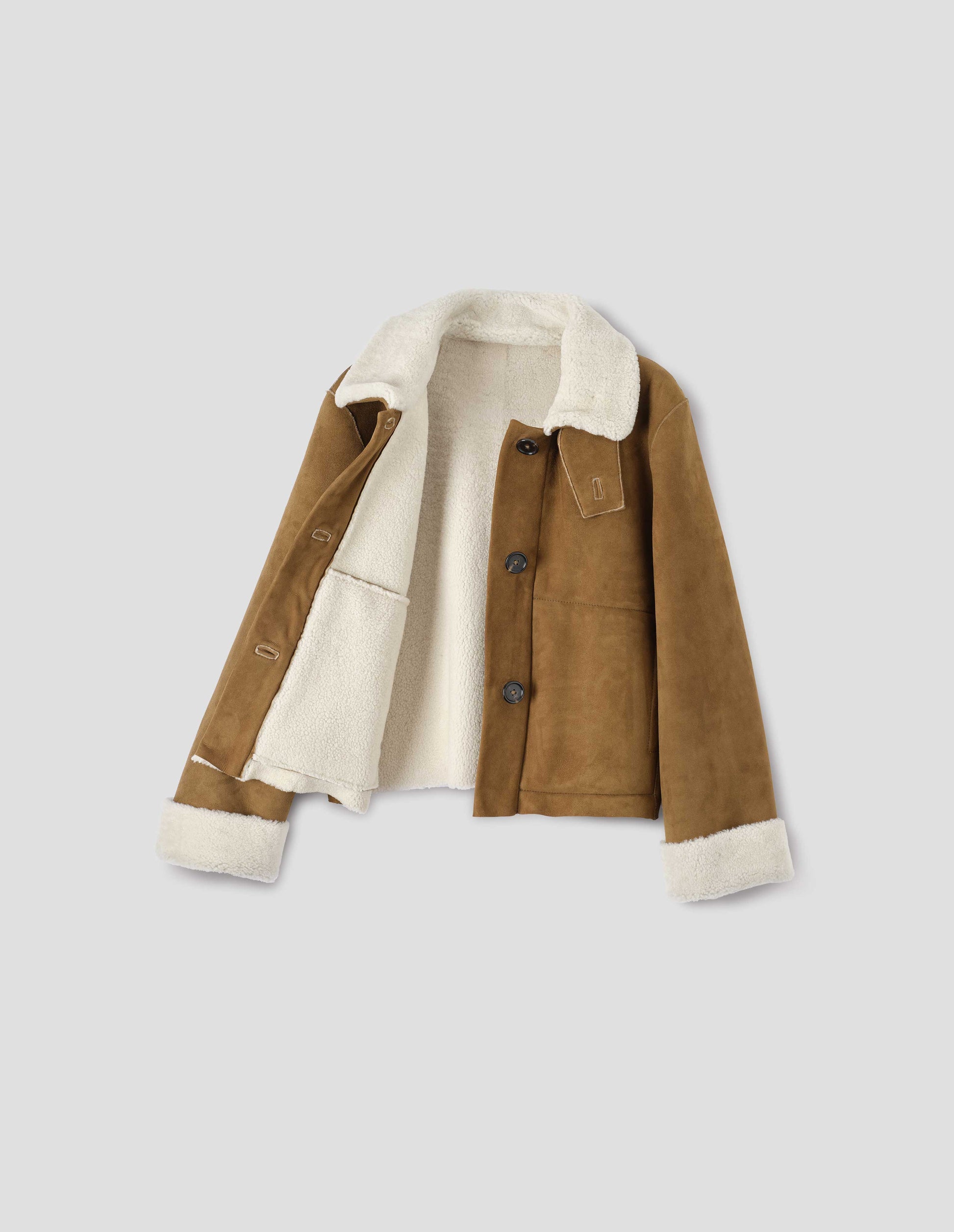 Tan and ecru shearling cropped jacket, with button tab fastening collar, turn back cuffs, side welt pockets and raw edge finishing on seams. Front flat lay open view.