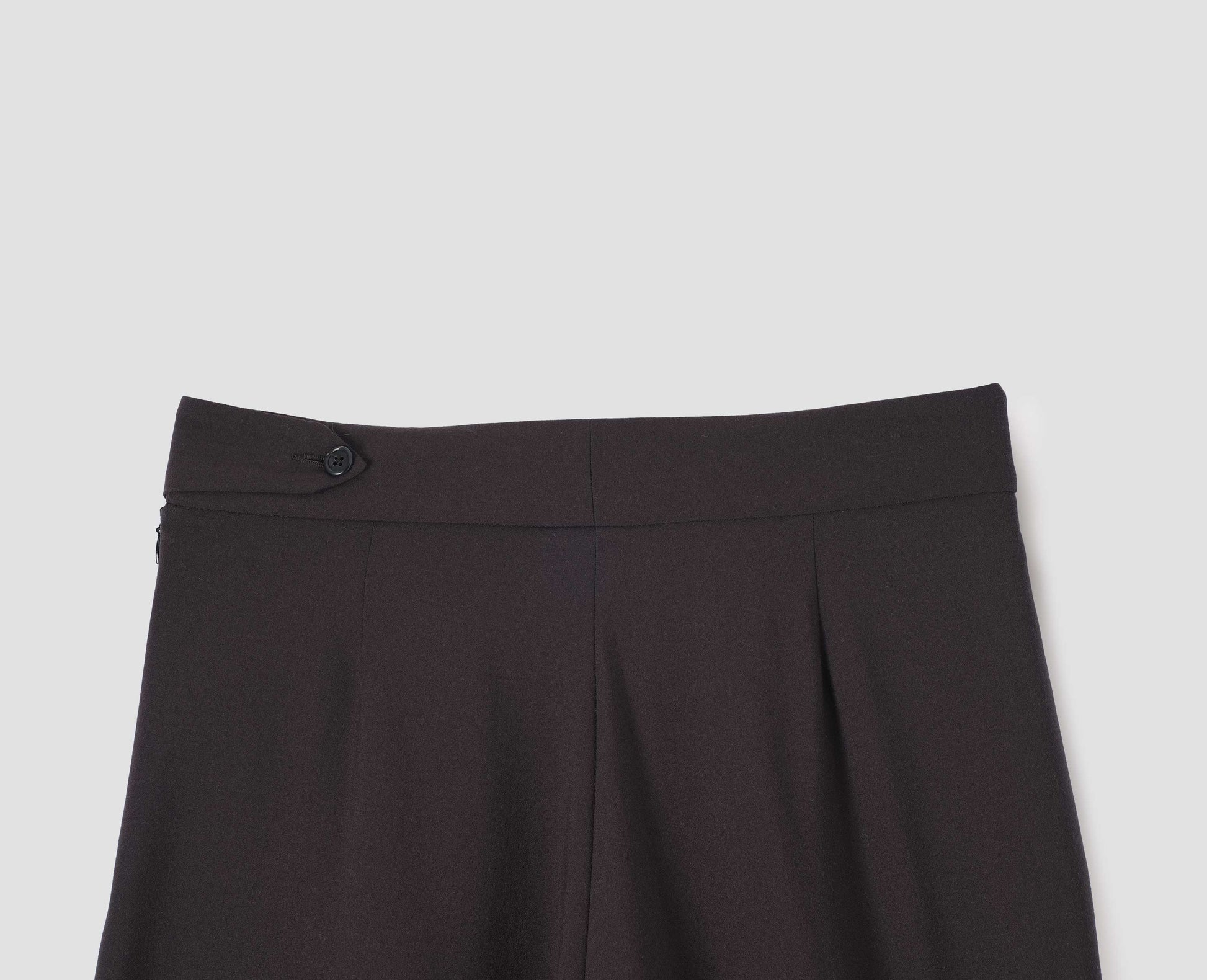 Brown double pleated wool trousers, with concealed side zip and pull through tab side fastening. Back flat lay view. 