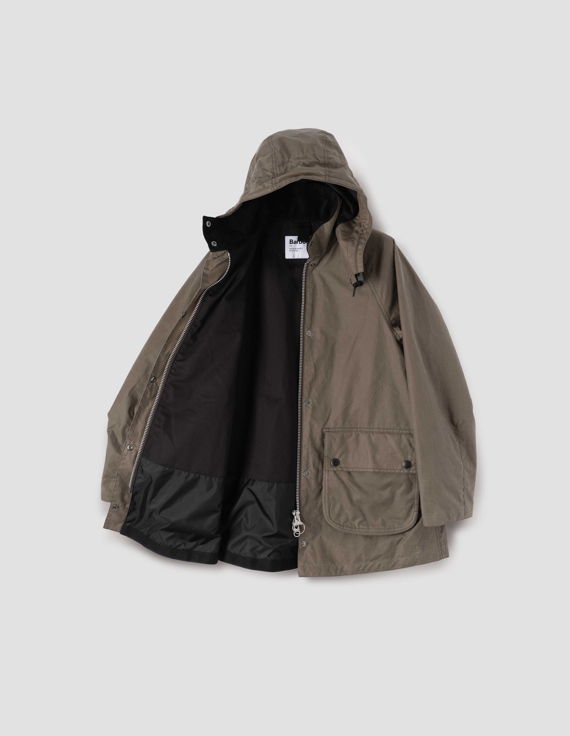 Dark beige cotton drill lined parka with stand collar and hood with wire adjustable peak, raglan sleeve, two way zip fastening, press stud fastening storm flap and large bellows pockets with press stud fastening envelope closure. Open flat lay view.