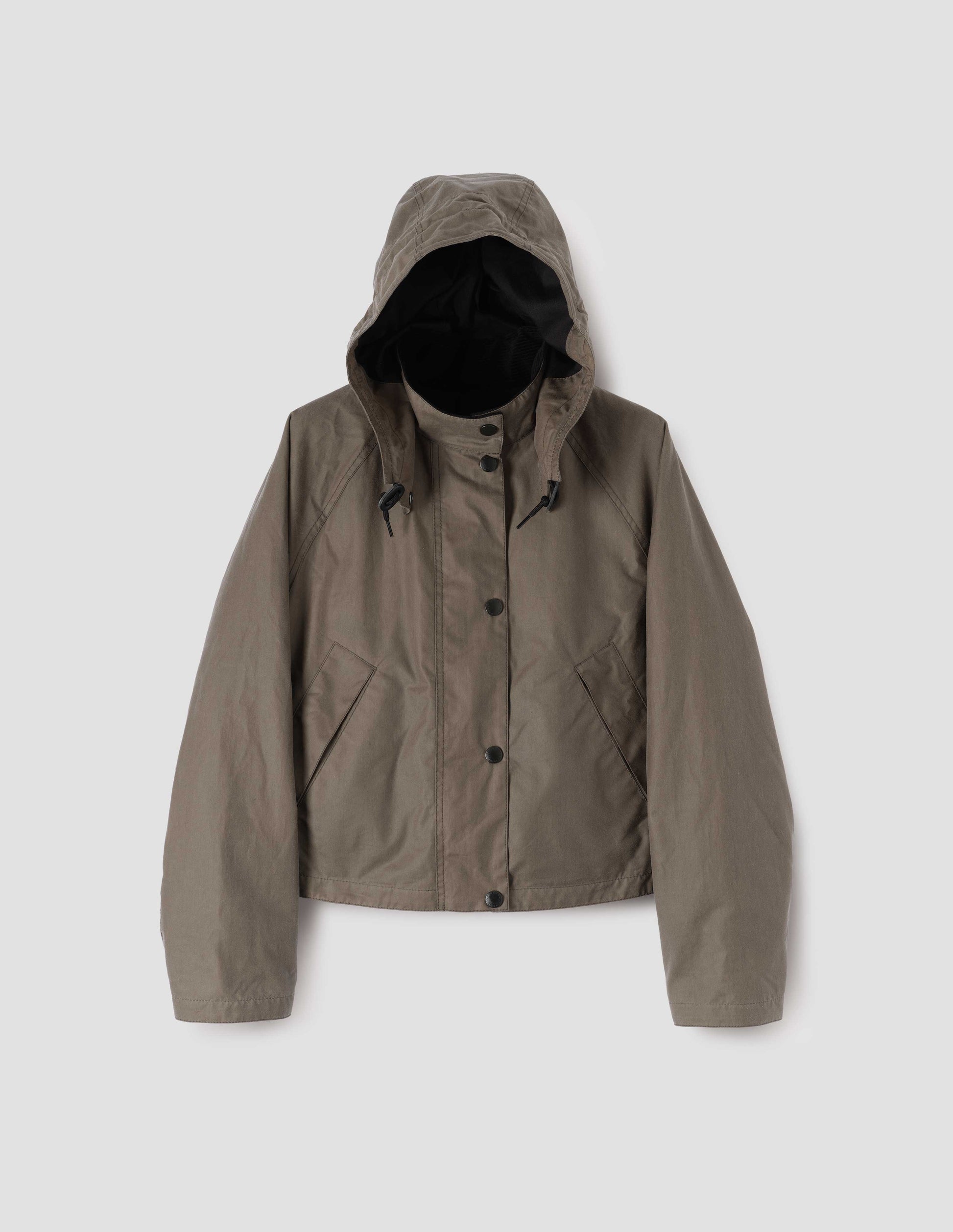 Dark beige cotton drill lined boxy jacket with stand collar and hood with wire adjustable peak, raglan sleeve, press stud storm flap and wide storm welt side pockets. Front flat lay view.