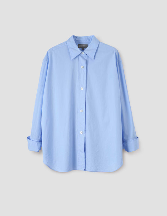 Light blue shirt with wide raised placket and mother of pearl buttons, and turned up cuffs. Front flat lay view.
