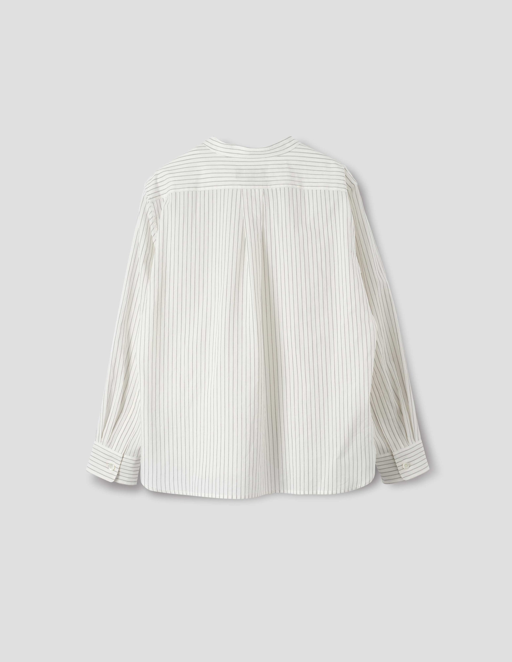 White collarless cotton and silk shirt with grey stripes, buttonhole detailing on collar band and box pleat on back yoke, mother of pearl buttons cuffs, elongated curved back hem. Back flat lay view. 
