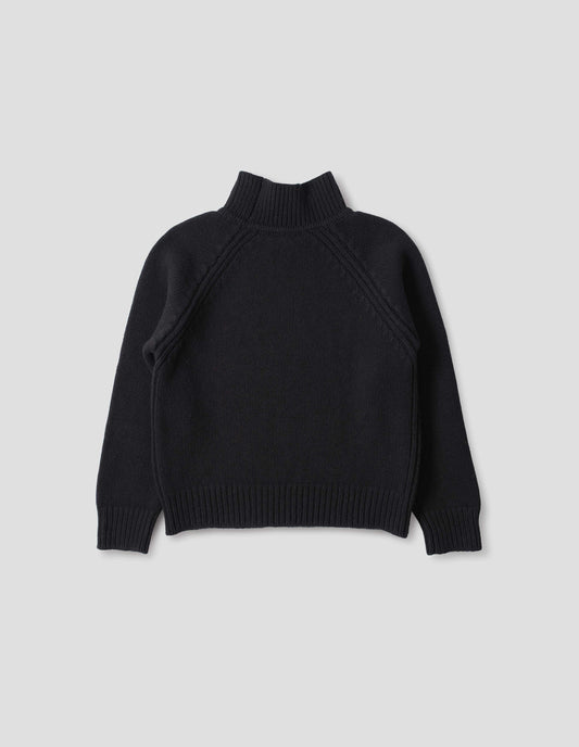 Black merino jumper with plain knitted back, raglan sleeves with ribbed side seams and ribbed high neck collar, cuffs and hem. Back flat lay view.