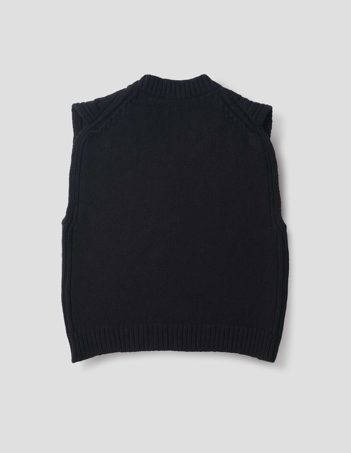 Black wool slipover with plain knitted back and ribbed neck, armholes, side seams and hem. Back flat lay view.