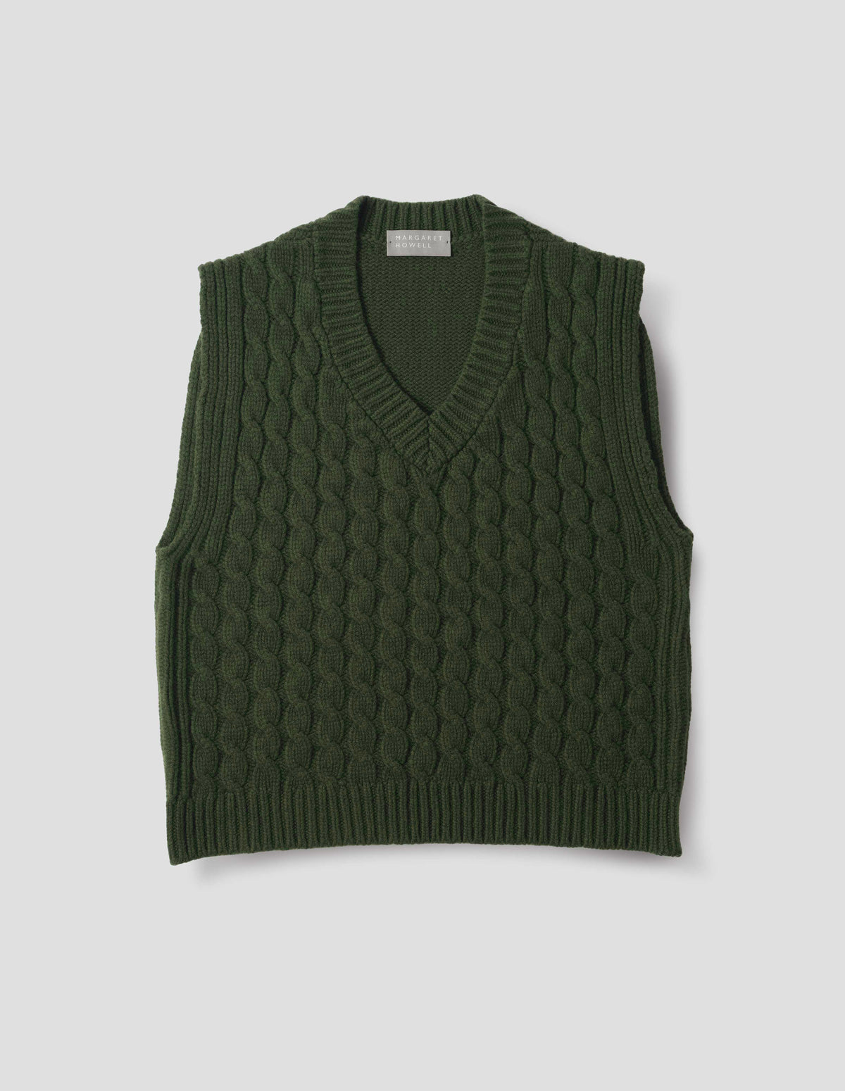 Green wool slipover with V neck, front cable design and ribbed neck, armholes, side seams and hem. Front flat lay view.