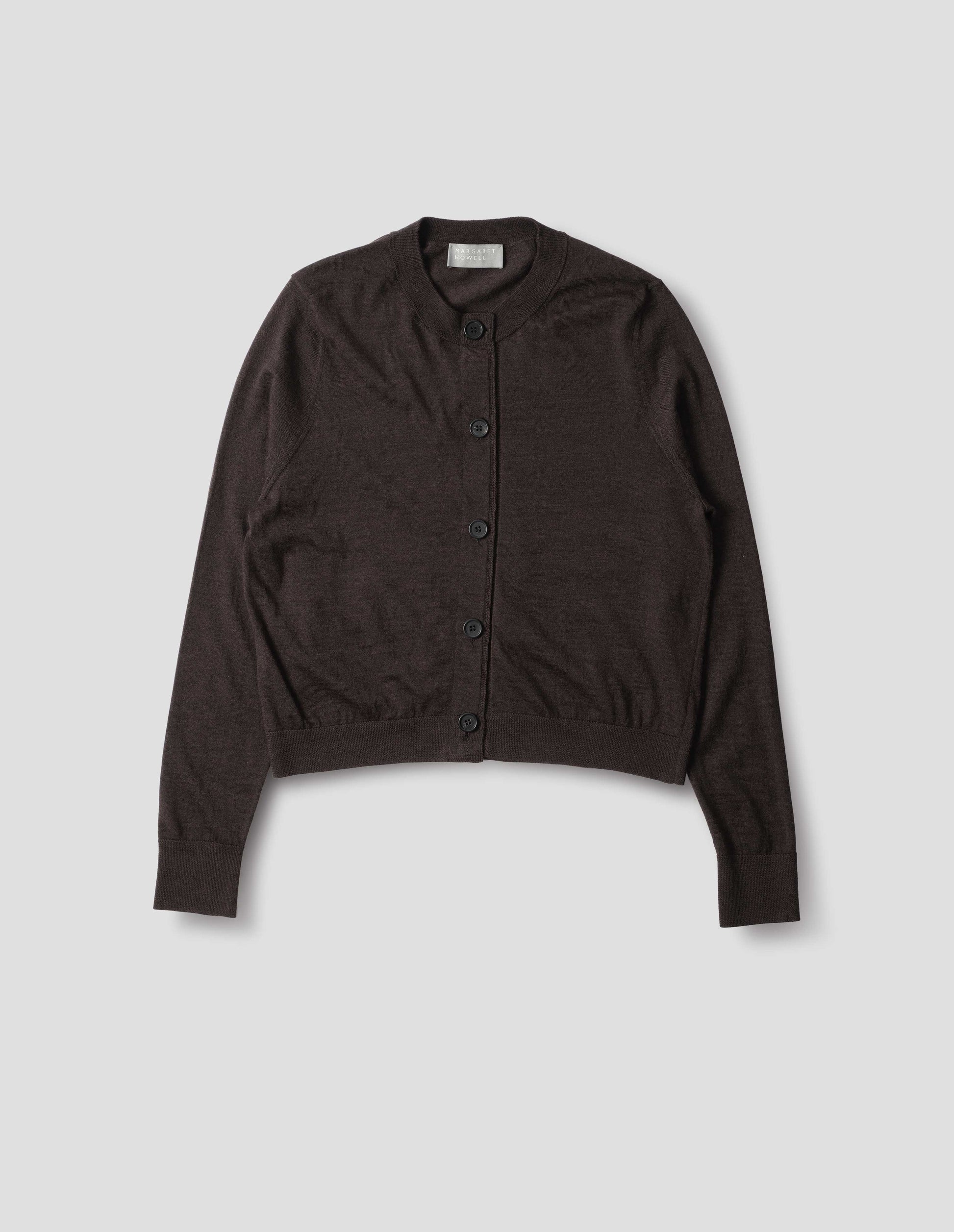 Dark brown merino cardigan with fully fashioned sleeves, horn buttons on concealed placket finished with grosgrain, and ribbed neck, cuffs and hem. Front flat lay view.