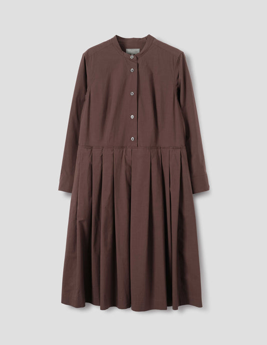 Brown collarless cotton dress with mother of pearl buttons on half placket, long sleeves with shirt cuffs, and pleated skirt with concealed side pockets. Front flat lay view.