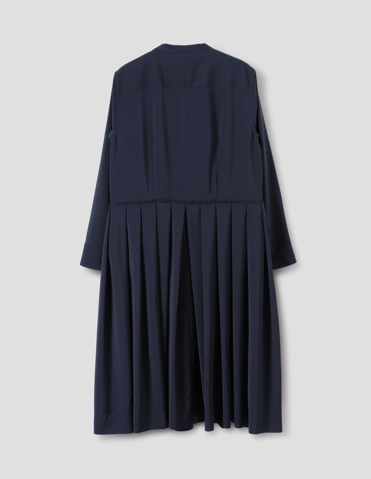 Dark blue collarless wool dress with shirt yoke, long sleeves with mother of pearl buttons on cuffs and pleated skirt with concealed side pockets. Back flat lay view.