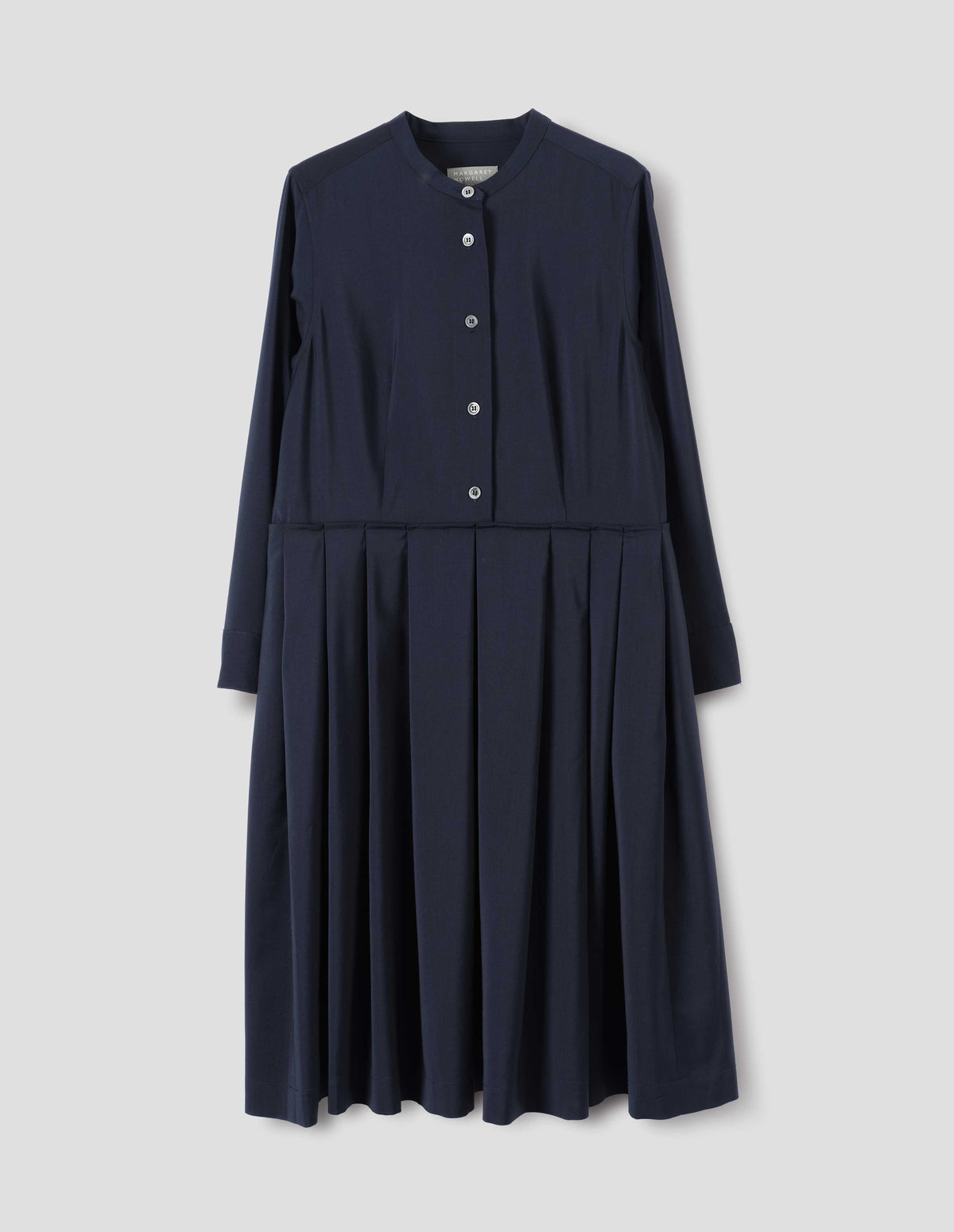 Dark blue collarless wool dress with mother of pearl buttons on half placket, long sleeves with shirt cuffs, and pleated skirt with concealed side pockets. Front flat lay view.