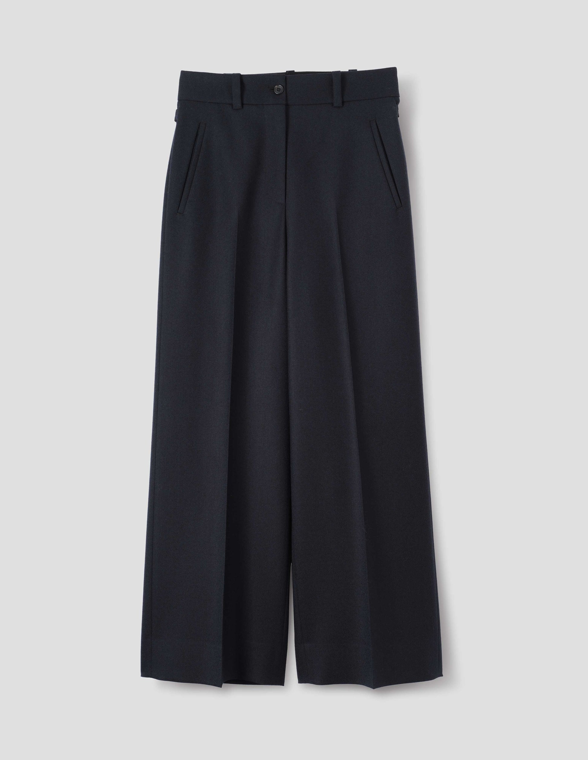 Dark blue wool trousers with wide waistband and belt loops, zip fly and horn button fastening, side adjusters and slanted front welt pockets. Front flat lay view.