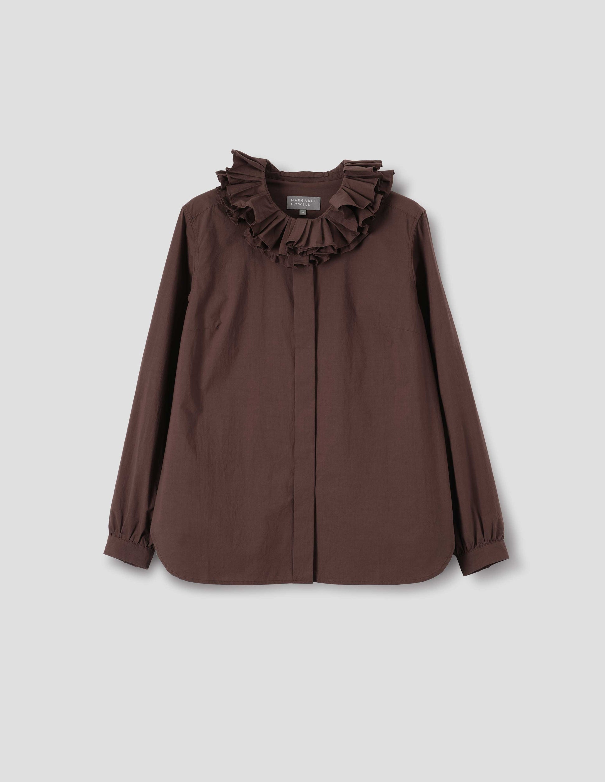 Brown cotton shirt with double ruffle collar, concealed placket with mother of pearl buttons, bracelet-length sleeves with mother of pearl buttons on narrow, gathered cuffs, and with curved hem. Front flat lay view.