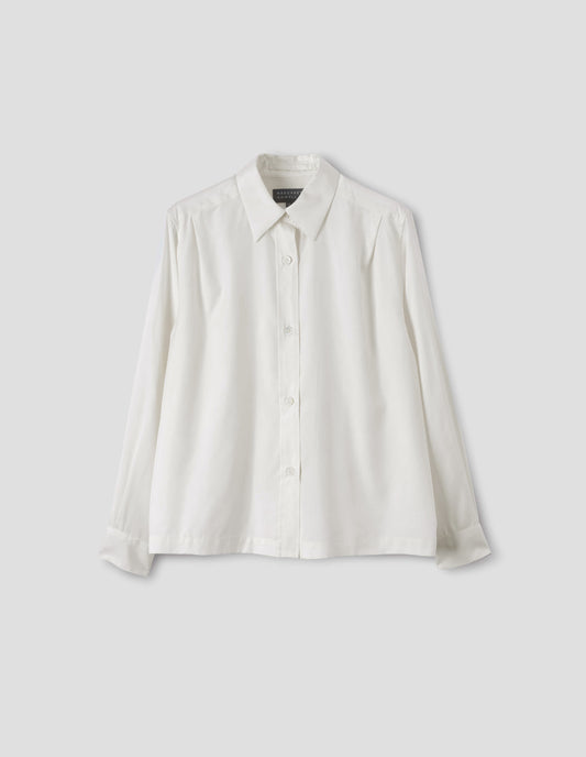 White silk shirt with mother of pearl buttons on placket and angled cuffs, narrow shoulder yoke with two pleats, and with vent split hem. Front flat lay view.