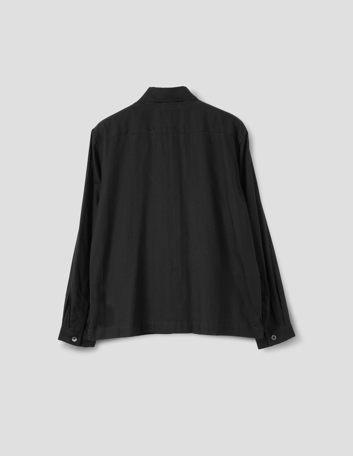 Black cotton cashmere sheer shirt with mother of pearl buttons on narrow cuffs with pleats and with square side split hem. Back flat lay view.